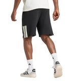 A person is photographed from behind against a plain background, wearing adidas All Blacks 26/27 Leisurewear Shorts with white stripes, paired with white adidas socks and white adidas sneakers.