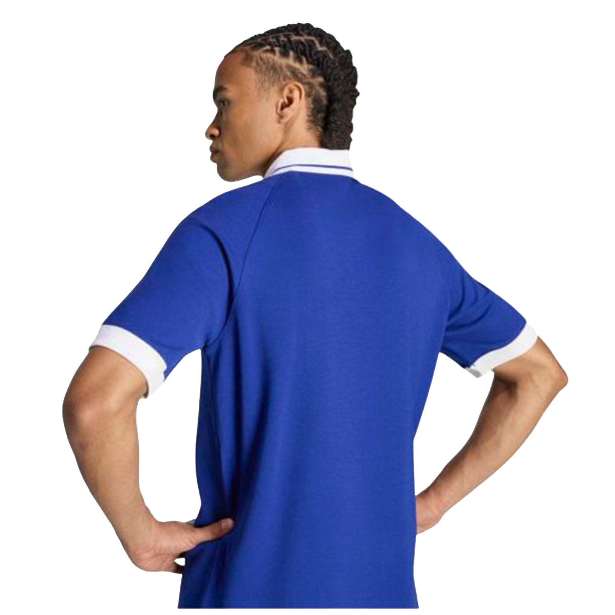 A person with braided hair stands with hands on hips, facing away from the camera, wearing the adidas France FFR 26/27 Travel Polo by adidas, featuring a blue design with a white collar and sleeve trim.