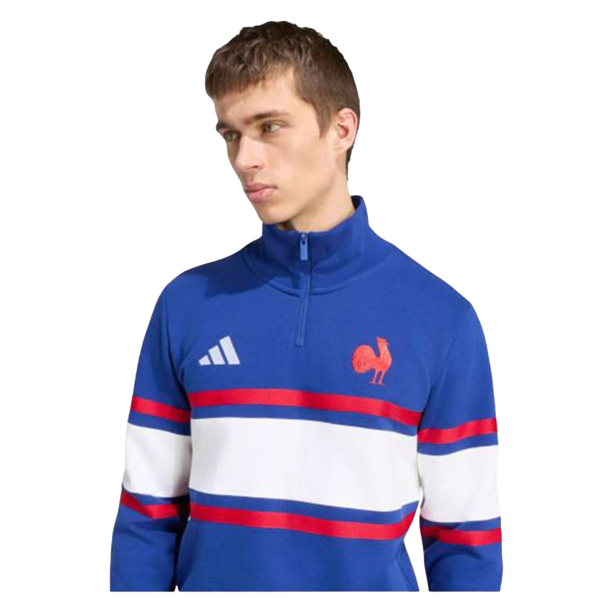 A young man wears the adidas France FFR 26/27 Travel 1/4 Zip Sweatshirt—a blue zip-up featuring signature white and red stripes, the adidas logo, and a bold rooster emblem—as he looks slightly to the side. This sweatshirt pairs sporty style with comfort, making it ideal for travel or relaxed occasions.