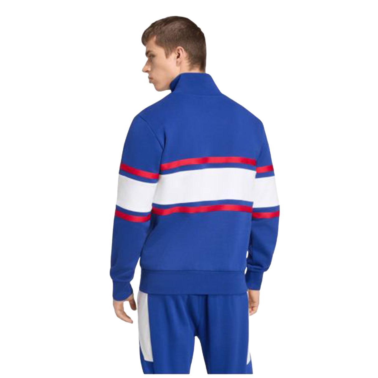 A person wearing the adidas France FFR 26/27 Travel 1/4 Zip Sweatshirt, featuring red and white stripes on the back, stands facing away from the camera.