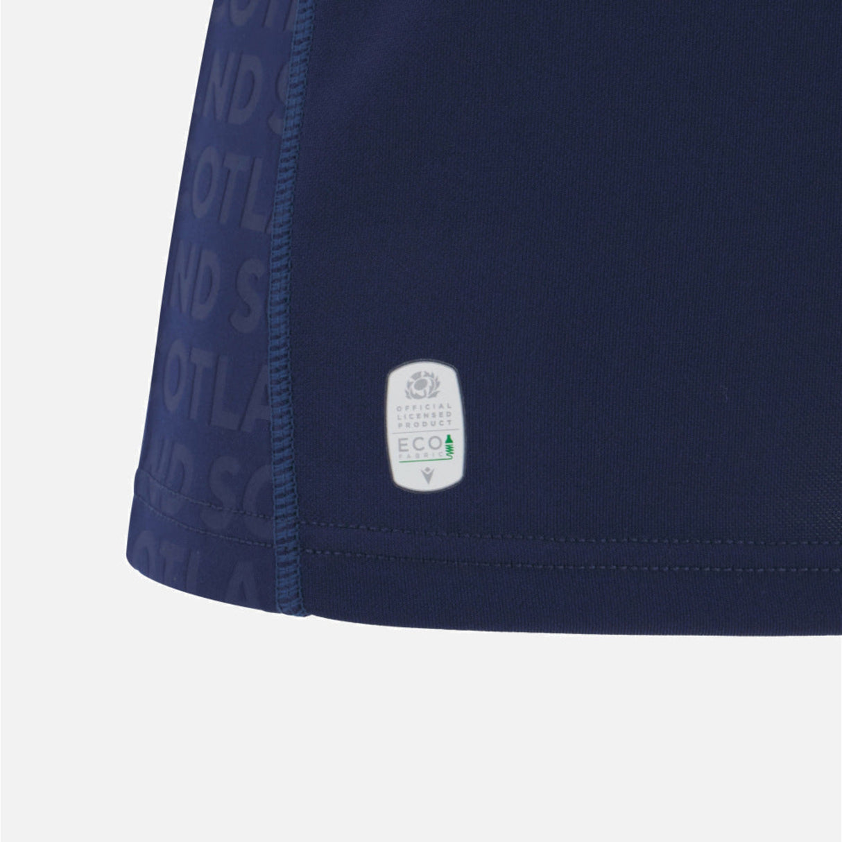 Close-up of the lower section of the Women's Scotland 25/26 Replica Home Jersey by Macron, featuring a small eco-friendly label and “SCOTLAND” text pattern along the side.