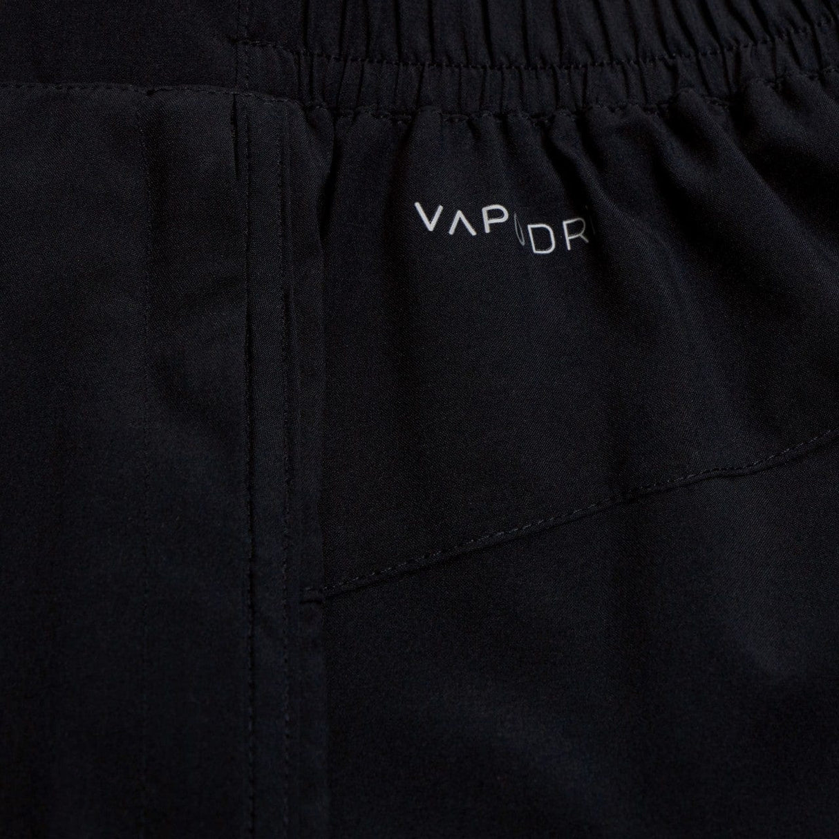 Close-up of black Canterbury Elite Woven gym short fabric with "vapor" logo embroidered in white.