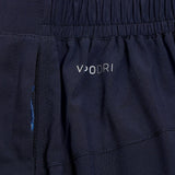 Close-up of dark blue Canterbury Elite Woven gym short fabric with a white "vuori" logo and a small blue zippered pocket.
