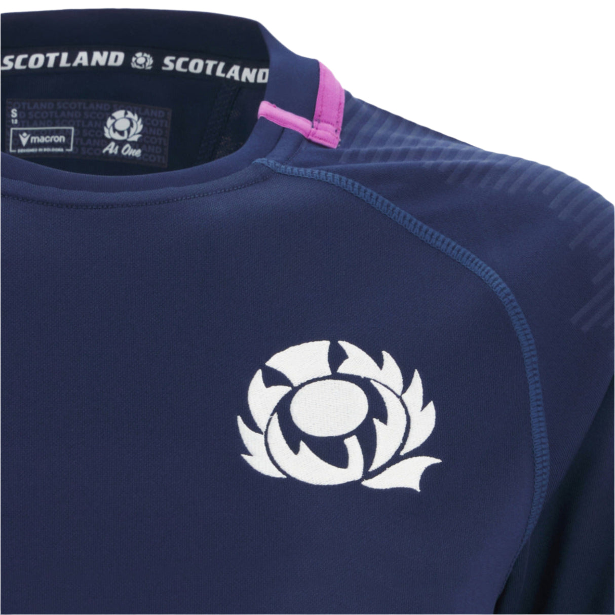 Close-up of the Women's Scotland 25/26 Replica Home Jersey by Macron in navy, with a white thistle emblem, Macron logo, and labeled collar with pink trim—an authentic home jersey.