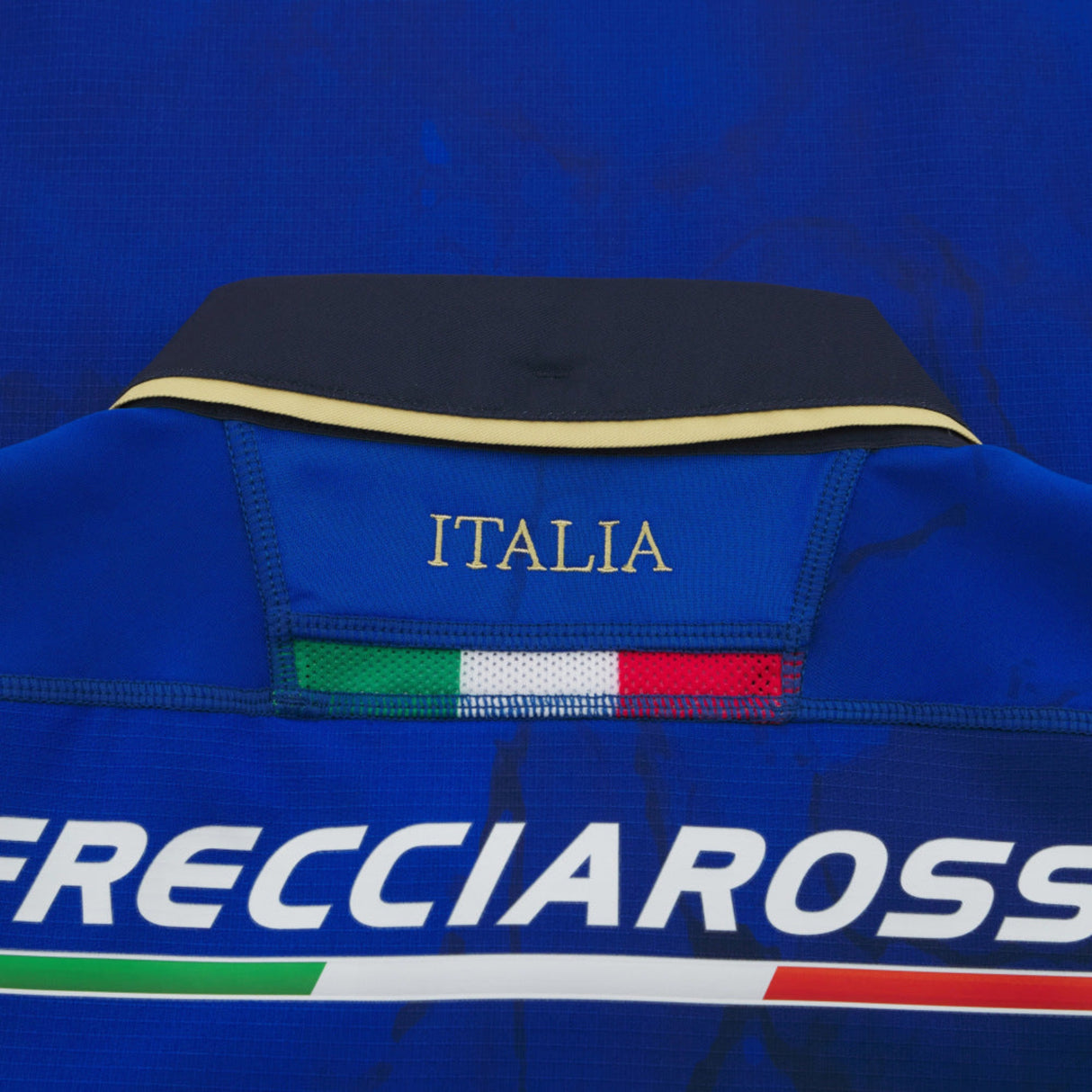 Close-up of the Italy 25/26 Authentic Home Jersey by Macron: a blue rugby jersey featuring "ITALIA" embroidered above the Italian flag and "FRECCIAROSSA" printed underneath.