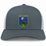 The Media Rugby Retro Trucker Cap by EMB S&S Activewear features a gray and white design with a front patch depicting a howling wolf, a full moon, and the words “MEDIA RUGBY EST 1973.” It is finished with a classic snapback closure for an adjustable fit.