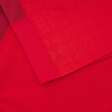 Close-up of overlapping red fabrics with varied textures, echoing the geometric patterns seen on the Wales 25/26 Authentic Matchday Home Jersey by Macron.