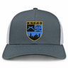 The New York Police Dept. Rugby Retro Trucker Cap by EMB S&S Activewear is a gray retro trucker cap with a mesh back and snapback closure, featuring an embroidered NYPD shield with a city skyline, scales of justice, and crossed batons on the front.