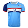 Light blue jersey with round neck and short sleeves. Right shoulder and sleeve in dark blue trimmed in red. Left sleeve in light blue trimmed in red. Fiji partial flags on upper left chest with Fiji Rugby in the center of red and dark blue horizontal lines.