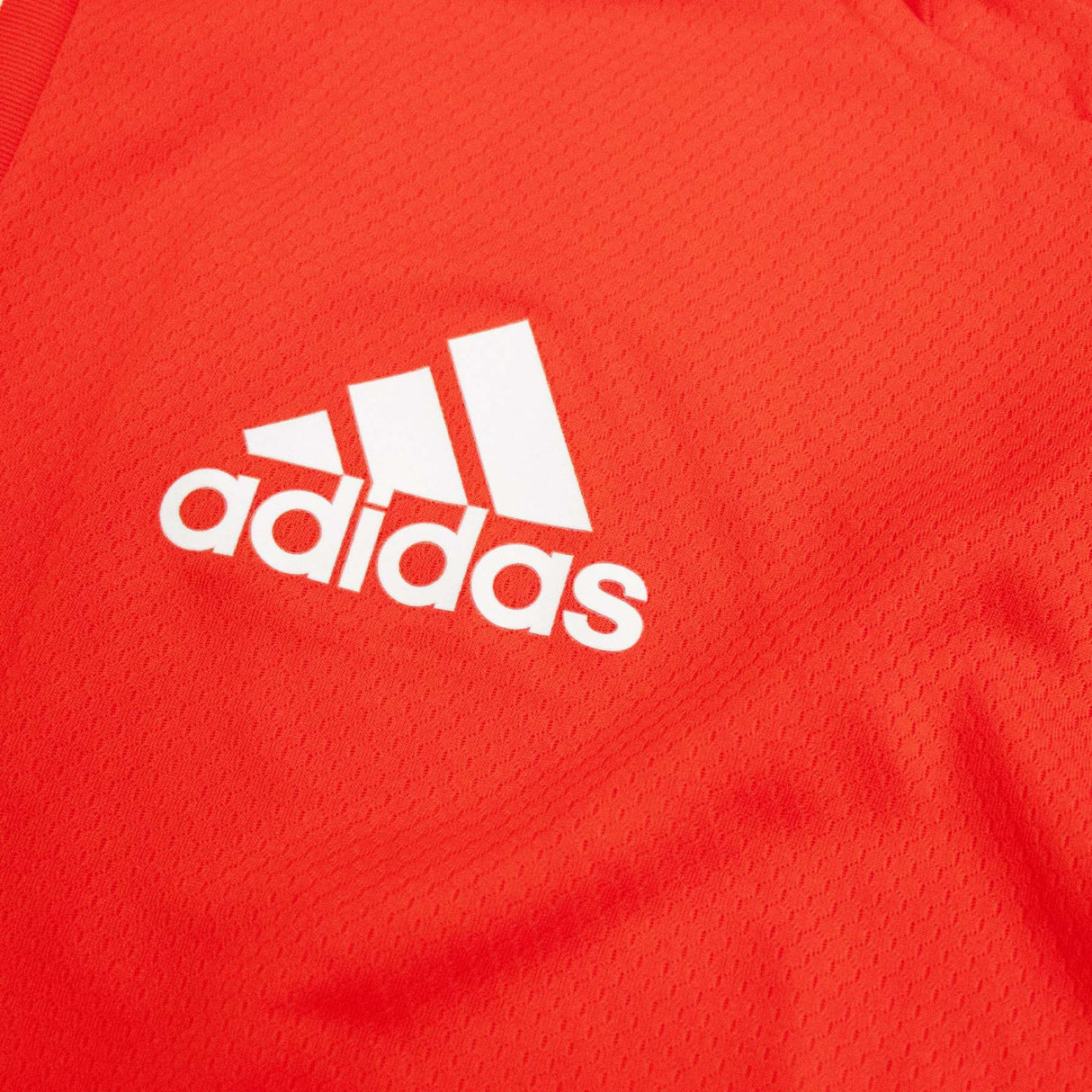A close up of the All Blacks Red Singlet by adidas logo on a red shirt.