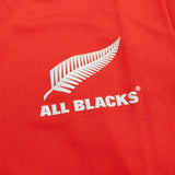 A close up of the All Blacks Red Singlet by adidas logo on a red shirt.