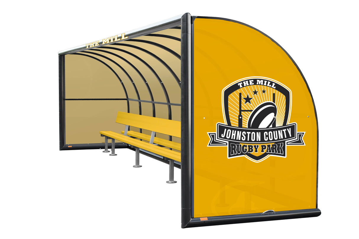 Yellow Kwik Goal bus shelter with "Johnston County Rugby Park" branding on its side and an aluminum bench under a curved roof, isolated on a white background.