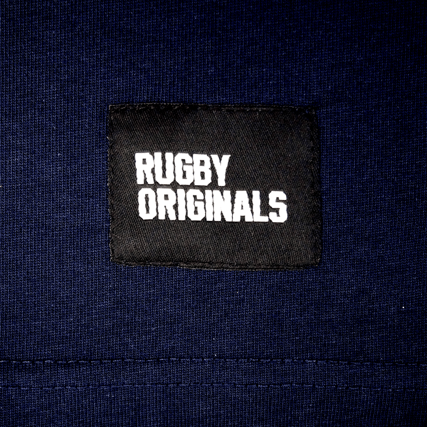 Detail of Rugby Originals on bottom of shirt.