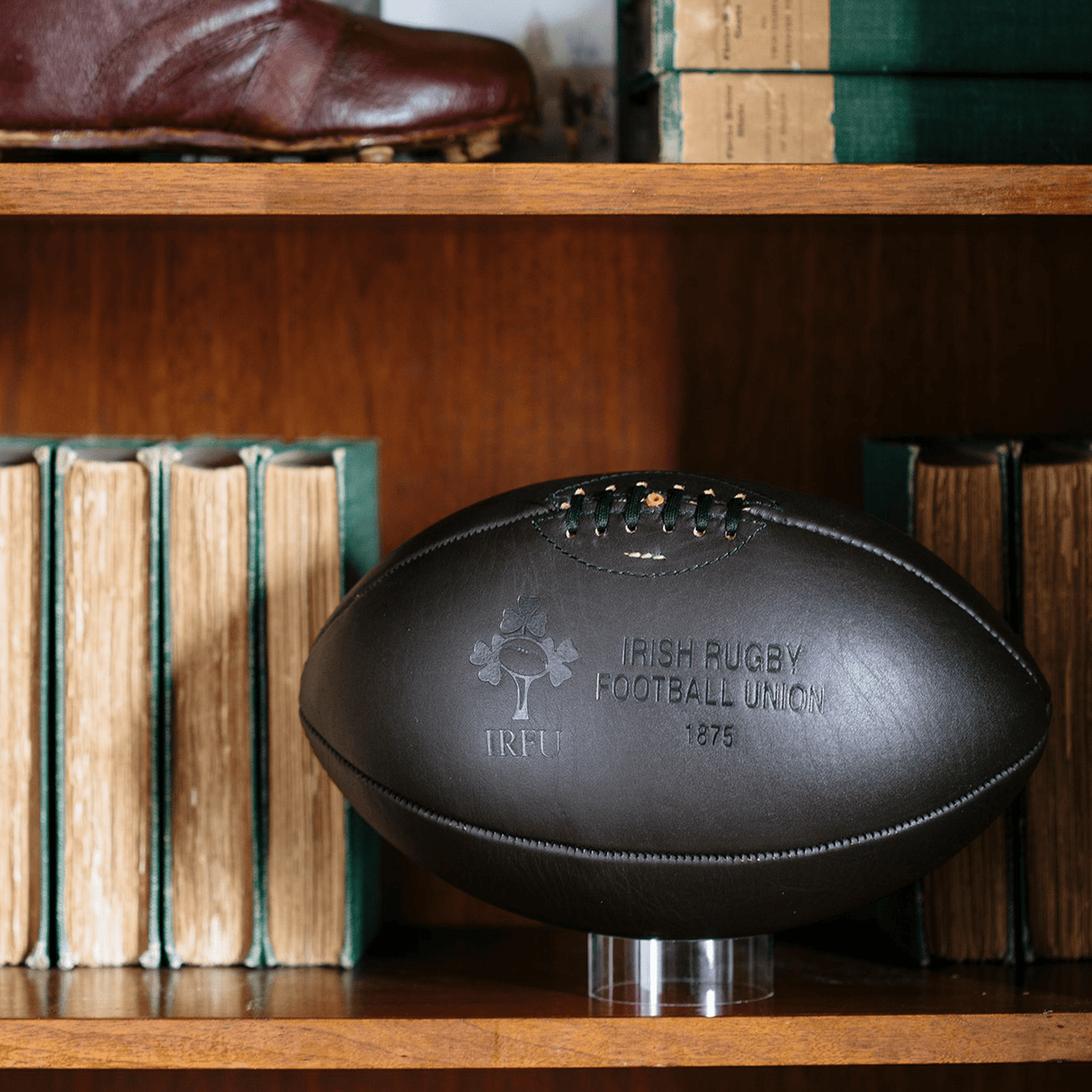 A Ireland 1875 Vintage Leather Ball by Gilbert is sitting on a book shelf.