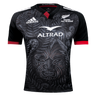 This Māori All Blacks Home Supporters Jersey by adidas comes in black and showcases an intricate Māori-inspired design. Made from recycled polyester, it features moisture-wicking fabric along with the Adidas and Altrad logos, and prominently displays the text "Māori All Blacks.