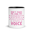White ceramic mug with black interior and a pink 'don't make me use my rugby mom voice' inscription.