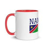Side view of white ceramic mug with red interior and handle and partial view of Namibia flag design.